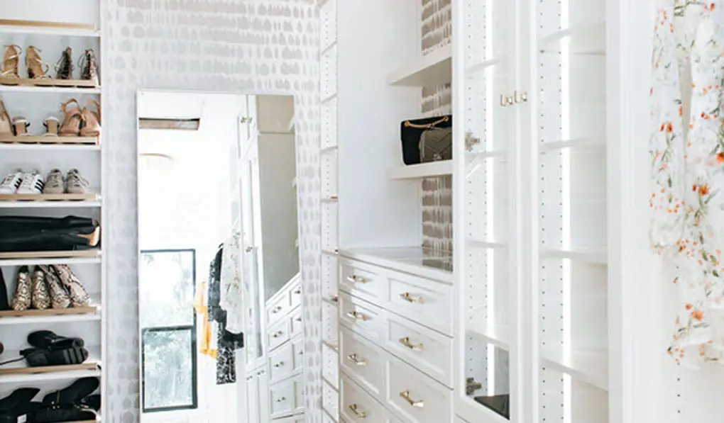 White Close with wall papered wall and gold hardware