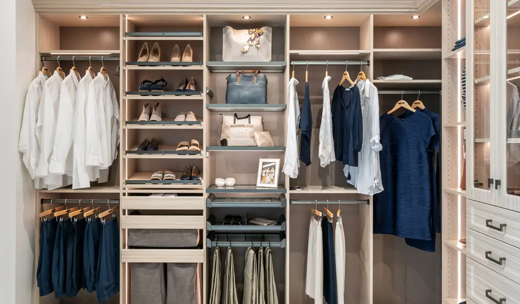 Light beige wood closet with glass shelves pull out drawers and lighting system