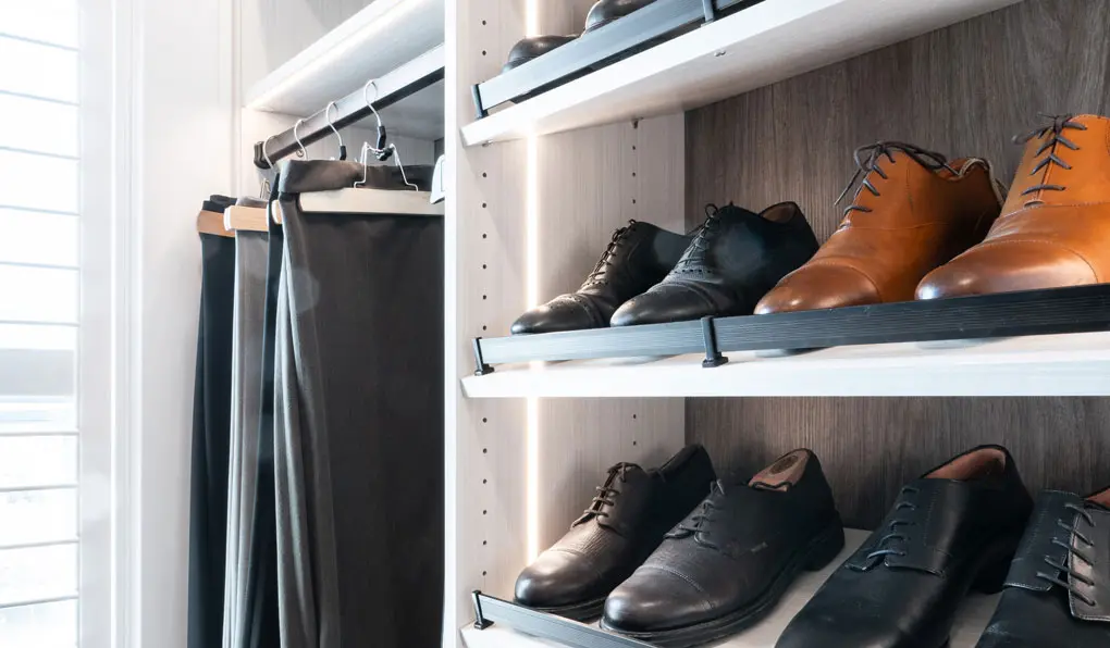 Men's shoes and pants hanging in a custom closet with led lighting system