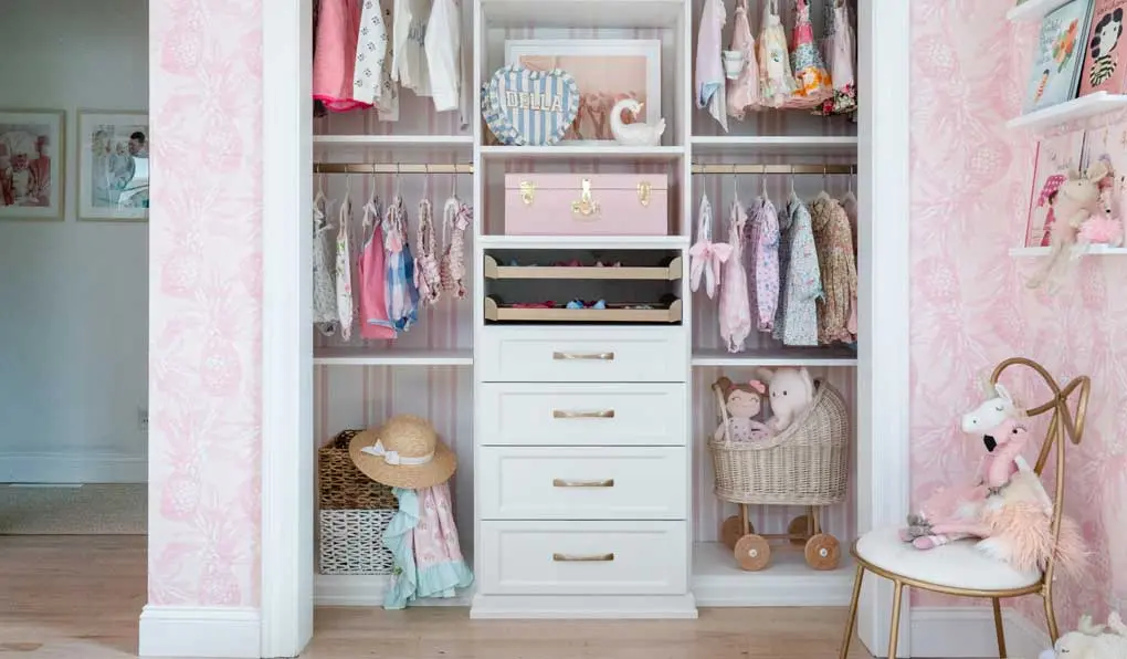 Custom child closet with shelves and pink accent and gold hardware