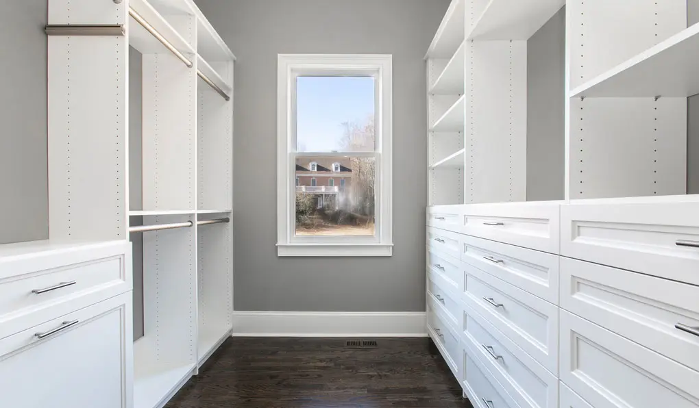 Empty custom closet with silver hardware and white shelves