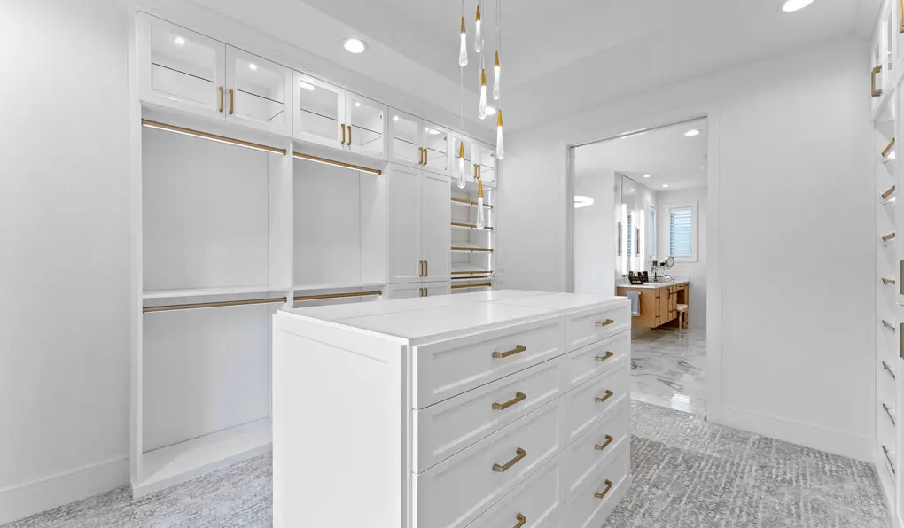 Empty closet organization solutions with cabinets and drawers and gold hardware